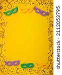 Small photo of Mardi Gras Masquerade festival carnival masks, gold color beads and golden, green, purple confetti on yellow background. Party invitation, greeting card, venetian carnival celebration concept