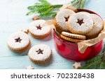 Traditional Christmas Linzer cookies with raspberry jam on blue wooden background.  Austrian biscuits filled. Selective focus. Holiday concept. Homemade sweet present in box