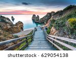 Wooden footbridge walkway to beautiful beach Praia do Camilo on coast of Algarve region, Portugal at sunrise