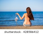 Beautiful woman on the beach in topless holding bikini