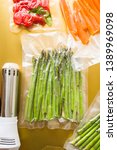 Small photo of Vacuum sealed vegetables , carrots, asparagus, tomato, on an orange background top view, ready to be cooked with sous vide sooner, with a automatic vacuum sealer machine and a rooner