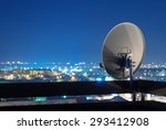 Satellite dish antenna on top of the building in urban area at night.
