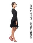 Small photo of Profile view of happy smiling Hispanic woman in black flounce dress looking at camera. Full body length portrait isolated on white background.