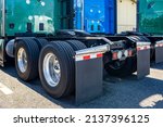 Small photo of Industrial grade powerful big rigs semi trucks tractors with double wheels on the axles with large tread pattern on tires for better grip standing on the truck stop parking lot