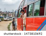 Small photo of Kathmandu / Nepal - September 26 2015: Nepali bus ticket collector stood in the doorway of a bus with a friendly thumbs up.