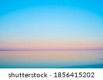 Calm sea water against cloudless sundown sky in summer evening in countryside