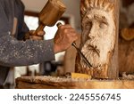 closeup of artisan wood worker sculpting carving a wood spirit face 