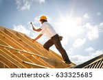 roofer working on roof structure of building on construction site