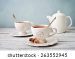 Cup of tea and sugar with teapot over blue background