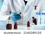 Small photo of researcher dosing and mixing fluid liquids in the chemistry lab. hands of chemist pipetting in a bottle drop of yellow fluid perfume in the product research laboratory
