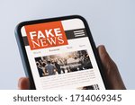 Small photo of Online fake news on a mobile phone. Close up of woman reading Fake news HOAX or articles in a smartphone screen application. Hand holding smart device. Mockup website. Fake Newspaper portal.