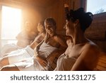Small photo of People relaxing and sweating in hot sauna wrapped in towel. Interior of Finnish sauna, classic wooden sauna with hot steam. Russian bathroom. Relax in hot bathhouse with steam.