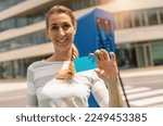 Happy woman holding Nfc or Rfid card on a  Hypercharger or Supercharger for electrical automobiles, with copyspace for your individual text. Charge electromobility concept image. 