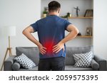 Small photo of Back pain, kidney inflammation, man suffering from backache at home, painful area highlighted in red