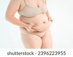 Small photo of Tummy tuck, flabby skin with stretch marks on a fat belly, plastic surgery concept on gray studio background