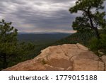 Evergreen trees are overhanging the edge of a rock outcropping, taken from FR 300 on the Mogollon Rim in Arizona.