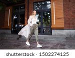 Beautiful Woman Wearing Fashionable Spring, Fall Clothes (beige trench coat, oversize khaki cargo pants, accessorie) Outdoors. Female stylish Model walking city Street. Autumn trend, fashion outfit