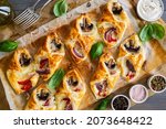 Baked puff pastry with mozzarella, white mushrooms and red bell pepper on baking paper 