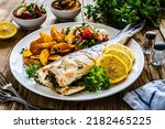 Small photo of Fried perch with boiled potatoes, lemon and fresh vegetable salad served on wooden table