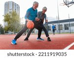 Small photo of Cheerful active senior couple playing basketball on the urban basketball street court. Happy living after 60. S3niorLife