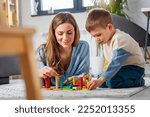 Small photo of Mother and her son playing on the floor with colorful didactic toys at home. Early education and development