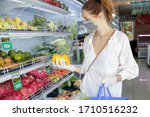 Small photo of Woman wearing protective mask and latex gloves while grocery shopping in supermarket, Coronavirus contagion fears concept