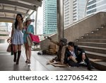 Small photo of Asian tourist women with many shopping bag look down on smell homeless dirty old guy and drunk businessman in urban city. bad habit for high society or gentility to disgust the poor.