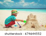 Small photo of little boy building sand castle on beach