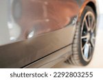 Small photo of Car dent after traffic accident or crash.Deformity lesion on the rear door of grey vehicle with space.Rear wheel with blur background and space.Insurance prompt to repair the car dent.Small dent.