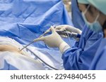Small photo of Team of doctor or surgeon and nurse in blue gown inside operating room did minimal invasive spine surgery technology with medical instrument.Disc surgery in sciatica pain.Close up at instrument.