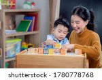 Small photo of Asian student in preschool use a letter box make a study word in class room with his teacher, this image can use for genius, clever, education and school concept.