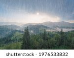 Rain and sun through the clouds over the green summer Carpathian foggy mountain hills. Rainy evening panorama.