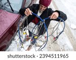 Small photo of Woman Examining Tire Chains, Confused Yet Determined to Tackle Unfriendly Winter Weather and Learn the Art of Installation in the Midst of Snowfall