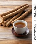 Small photo of Burdock tea placed against a background of wooden boards. A raw burdock behind it