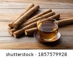 Small photo of Burdock tea placed against a background of wooden boards. A raw burdock behind it