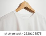 Small photo of Close up shot of round neckline of a white roundneck t-shirt mockup on wooden hanger