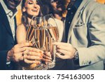 Men and women celebrating birthday or new years party while clinking glasses with sparkling wine