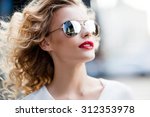 Portrait of a beautiful young blonde woman in sunglasses in the city