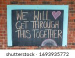 Small photo of Chalk sign saying will get through this together on a brick wall. Written during the Coronavirus pandemic lockdown.