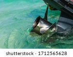 Close up stainless steel motor boat propeller on turquoise sea water background.