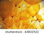 Background of  bright yellow inflatable balloons up in the air, backlit by sun.