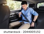young man fastening a seat belt while sitting in the back seat of car 