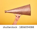 woman hand holding an old megaphone on a yellow background