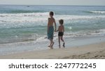 Small photo of Children with back play with waves going back and forth, waving sea
