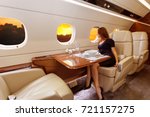 young beautiful woman in Luxury interior in bright colors of genuine leather in the business jet, sky and rays of sunset through the porthole