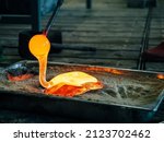 Small photo of Creating traditional glass Art. Melting glass mould into sand form. Manual glass processing by the craftsmen inside a glass factory