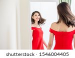 asian girl trying red dress and looking in mirror cheerful 
