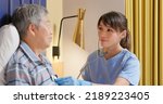 Small photo of people home healthcare concept - asian female nursing assistant is using stethoscope to examine senior man who is lying on bed and they nod heads