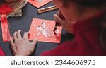 Small photo of back view of asian woman write spring festival couplet to celebrate Lunar new year with word meaning Dragon