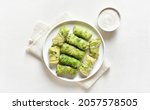 Small photo of Stuffed cabbage rolls with sauce over white stone background. Top view, flat lay